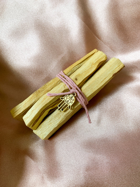 Ce petit lot de 5 bâtons de Palo Santo, joliment emballé avec du jute naturel et décoré avec une breloque en or Hamsa en forme de main sera parfait pour purifier votre intérieur, chasser les énergies négatives ou vous protéger pendant vos rituels. Il est proposé par la marque Sacred Space.